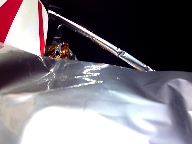 Close-up of a metallic surface with a partial view of a striped structure and a pole against a black...