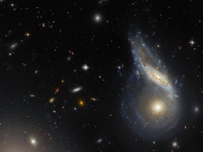 Two spiral galaxies are merging together at the right side of the image. One is seen face-on and is ...