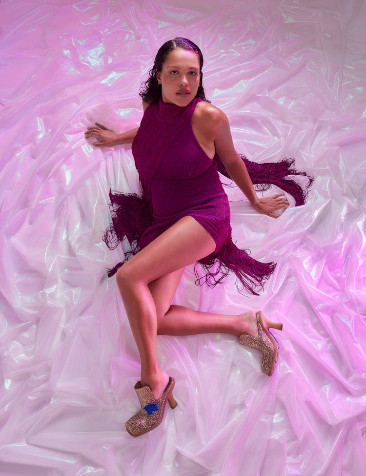 Model Alva Claire wears a purple short fringed dress and glitter platform shoes.