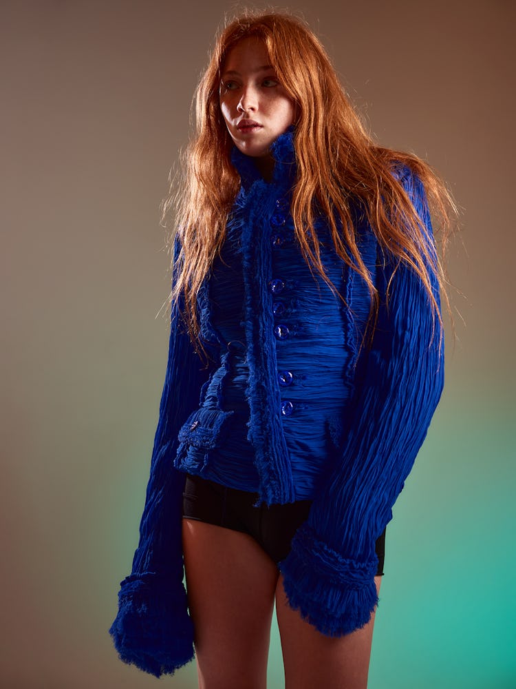Model Stevie Sims wears a blue wrinkle military jacket and black shorts. 
