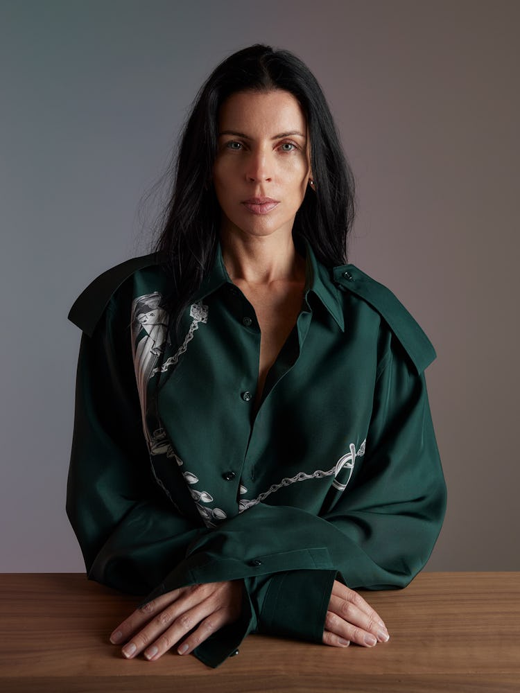 Model Liberty Ross wears a green silk blouse and gold earrings.