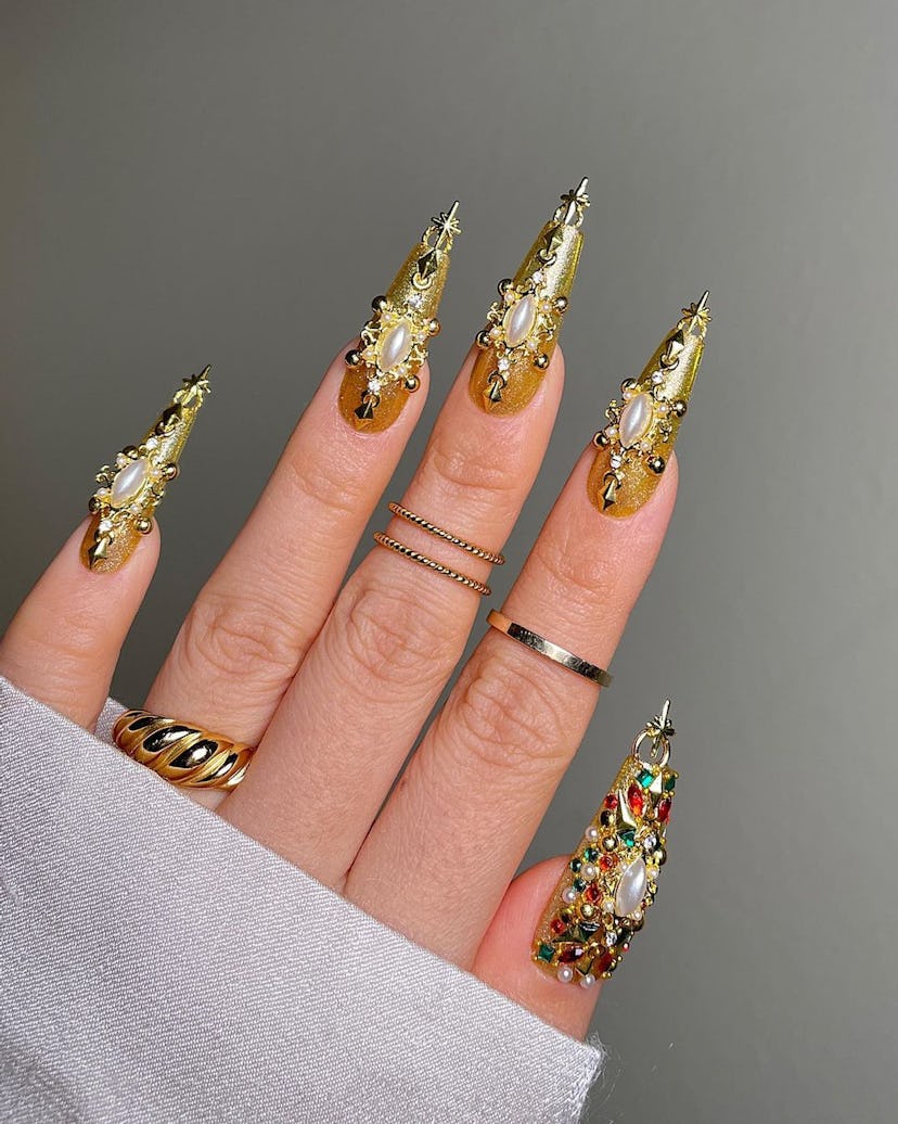 Decadent gold chrome nails with gilded gems and pearls match the mob wife aesthetic.