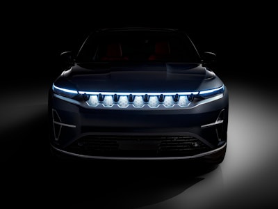 A modern car with distinctive LED headlights illuminated, showcased in a dark background, hinting at...