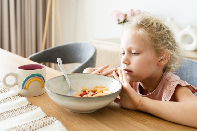 A child pushes away their plate of food.