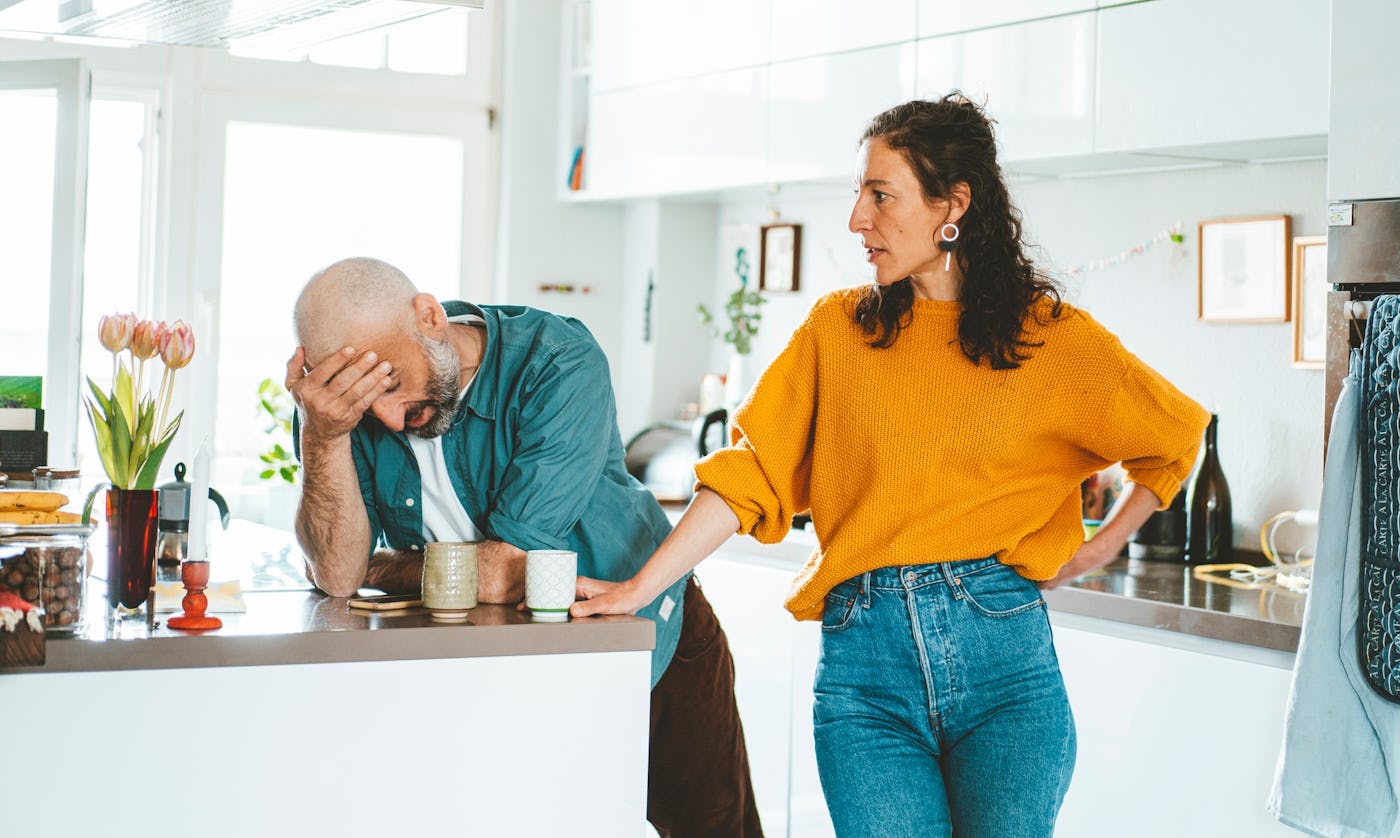 A man and woman argue in the kitchen.