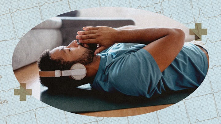 A man practicing yoga nidra, lying on a yoga mat on his living room floor, wearing headphones.