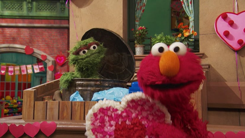 Elmo and Oscar stand amid Valentine's Day decorations on Sesame Street.