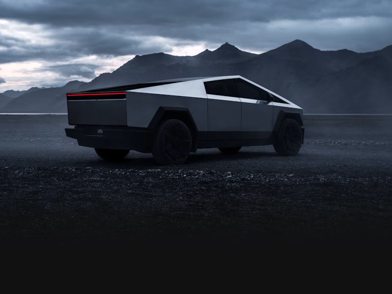 A futuristic electric pickup truck with a geometric design, parked on a desolate landscape with dark...
