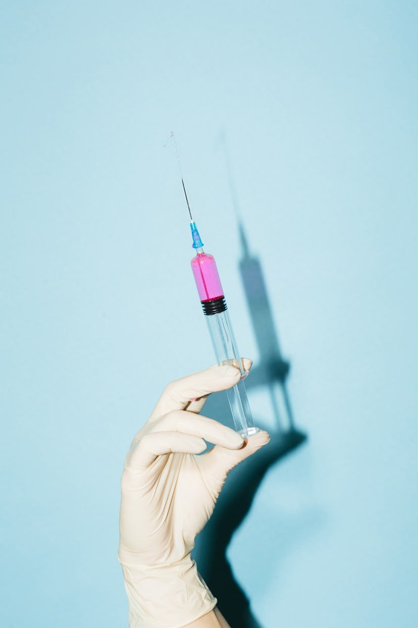 a gloved hand pressing a syringe