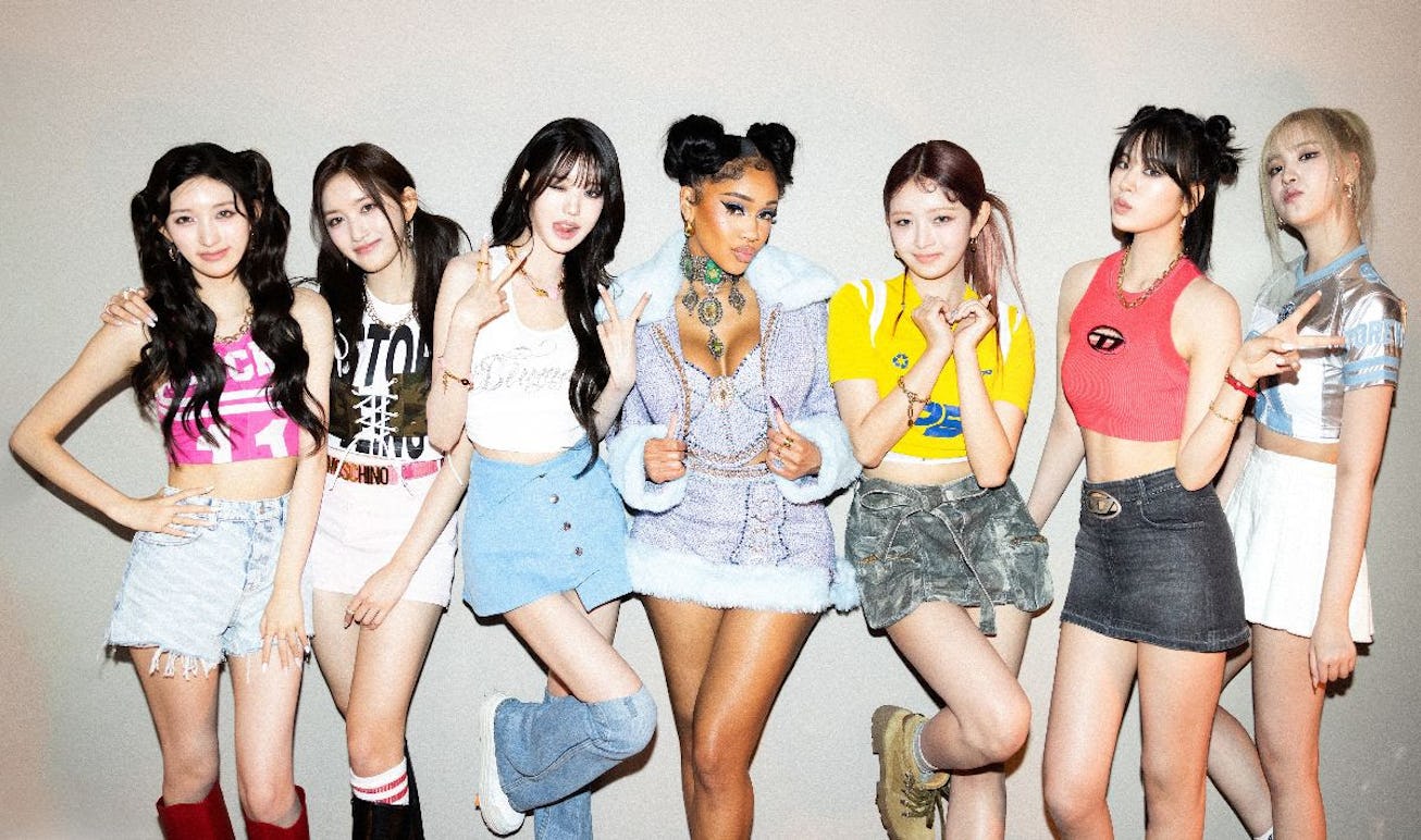 Six women from a music group and a featured artist pose together, sporting trendy outfits with a mix...