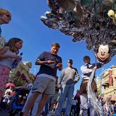 A dad pays for souvenir balloons at Walt Disney World.
