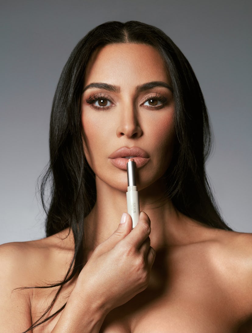 Kim Kardashian holds lipstick near her lips, while discussing her first makeup collection for SKKN B...