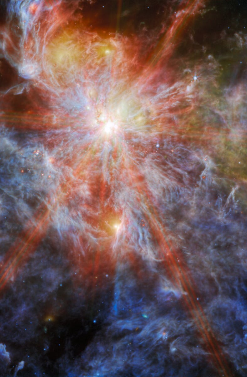A bright young star within a colourful nebula. The star is identifiable as the brightest spot in the...