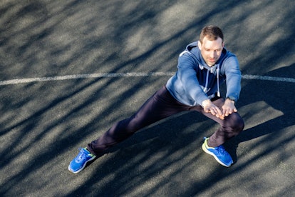 A man doing lateral lunges outdoors on blacktop.