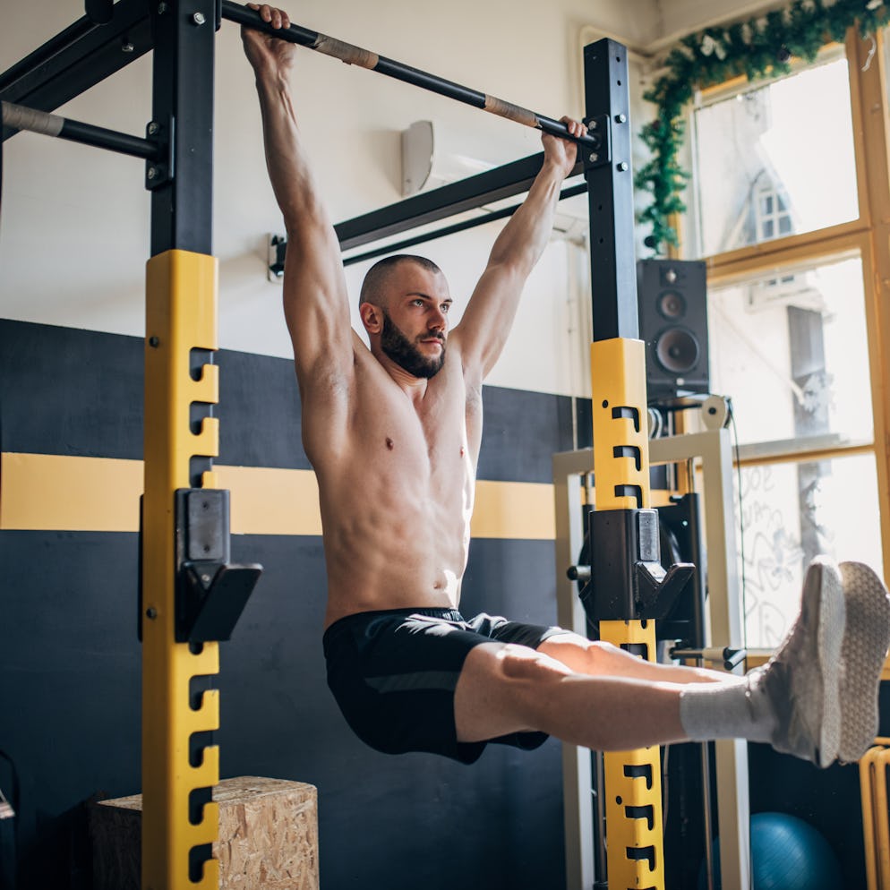 A man doing hanging leg raises in a home gym.