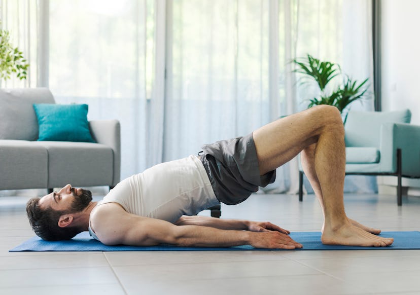 A man doing a bridge exercise on a yoga mat during a Pilates workout.