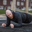 A man doing a plank exercise at an outdoor gym during his Pilates workout.