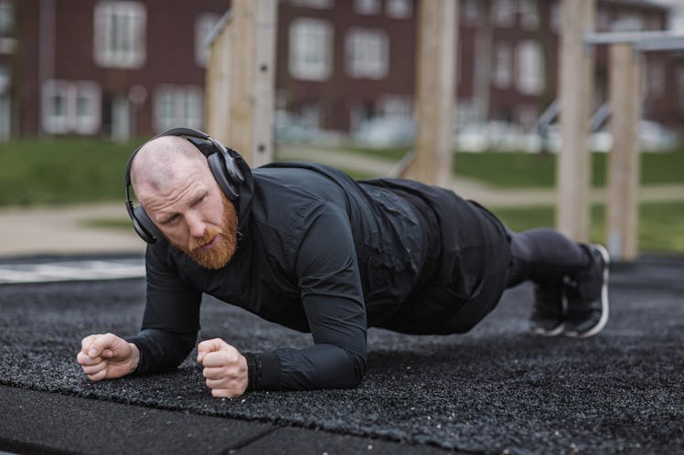 A man doing a plank exercise at an outdoor gym during his Pilates workout.