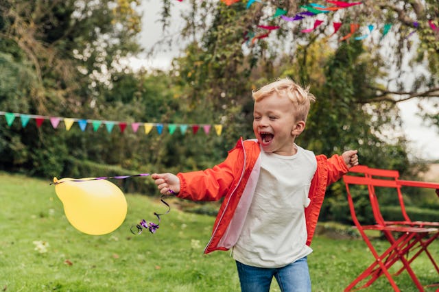 A little boys runs around outside at a birthday party.