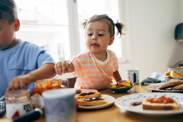 A toddler eats dinner of toast and toppings.