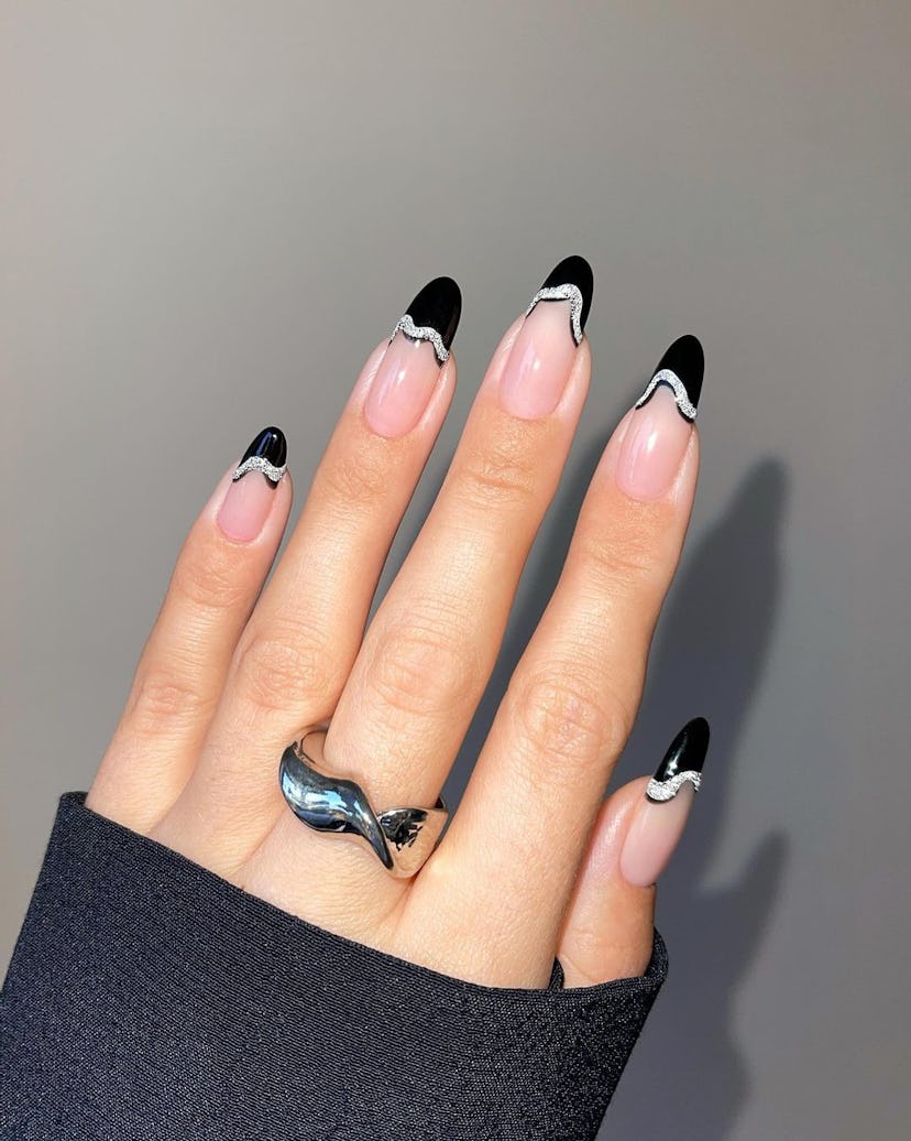 Abstract black French tip nails lined with silver glitter polish is on-trend for 2024.