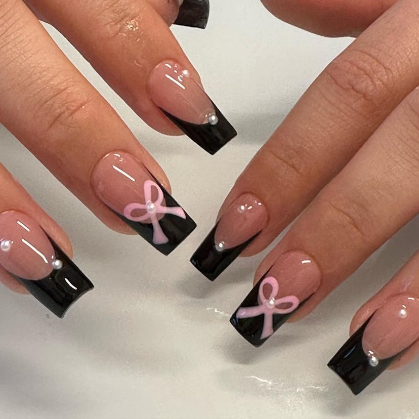 Chunky black French tip nails with pink ribbons are on-trend for 2024.