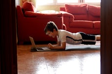A young boy holds a plank while exercising.