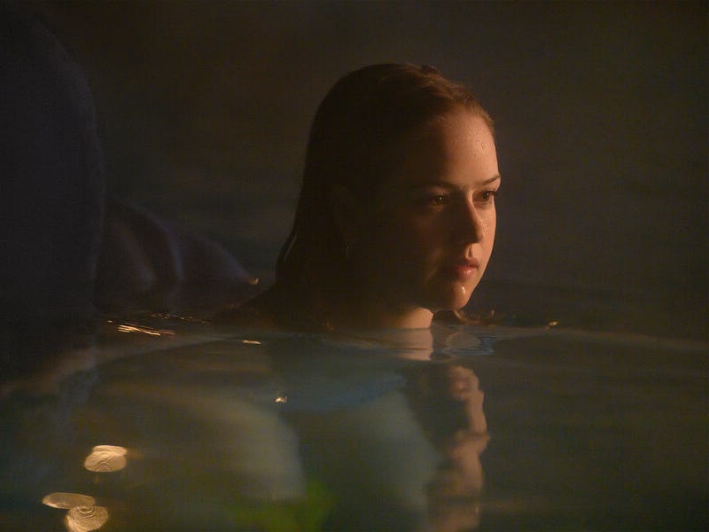 Woman in water with mist around, reflecting on life with a contemplative look.