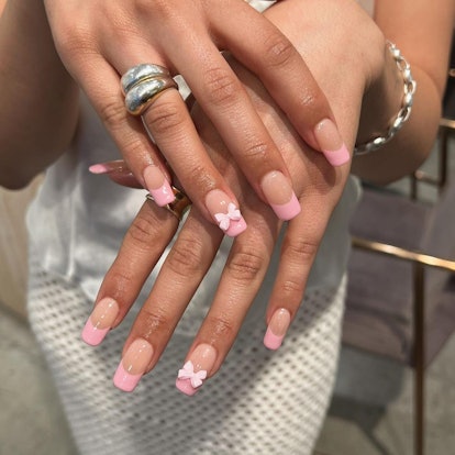 Pontas francesas rosa com arte em arco coquete são uma ideia moderna de manicure francesa para 2024.