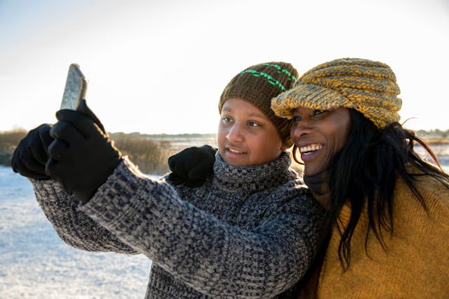A mom and her teen son take a photo outside in the snow.