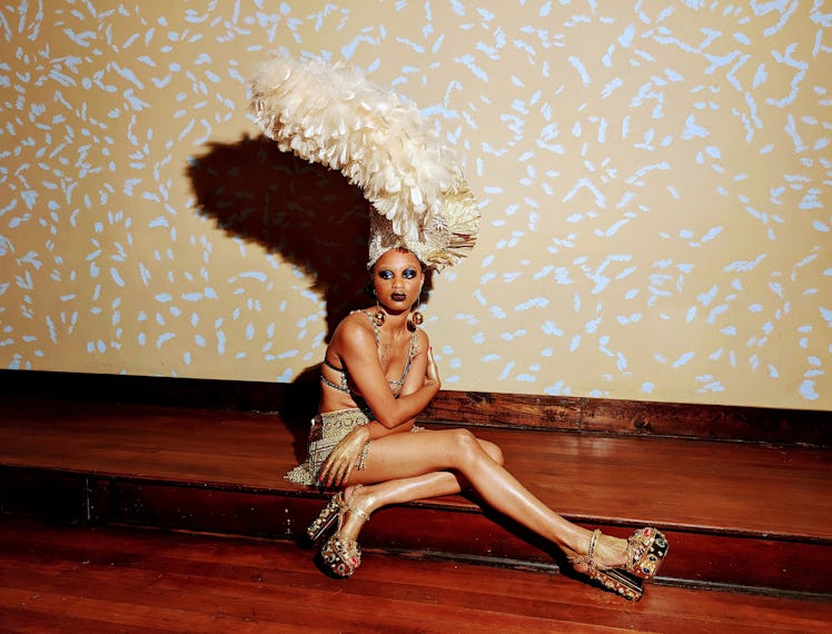 a person sitting on a step with a big cream colored feathered headdress