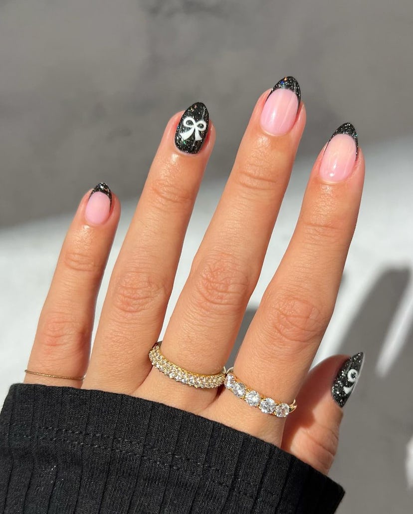 Black glitter French tips with painted-on ribbons are a trendy French manicure idea for 2024.