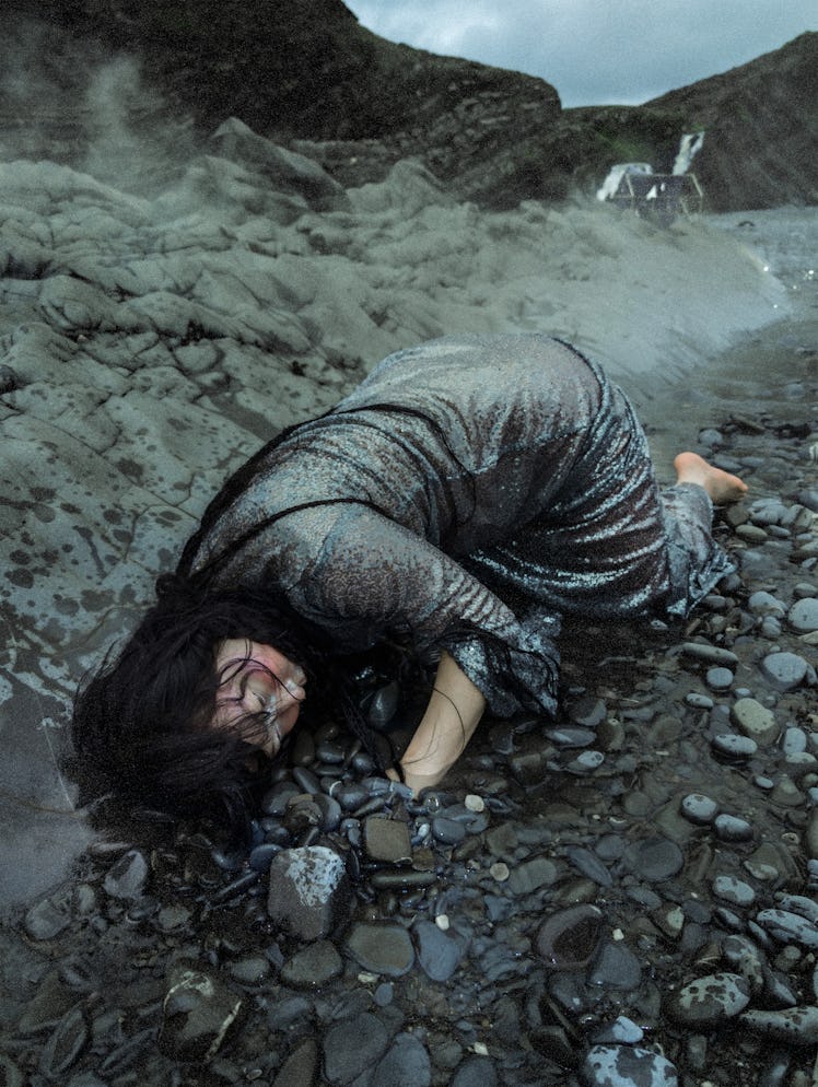 a photograph of a person in a silvery gray sparkling dress, their head on the ground while they lie ...