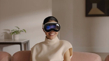 A woman wearing Apple Vision Pro with here eyes displayed through the EyeSight feature using the ext...
