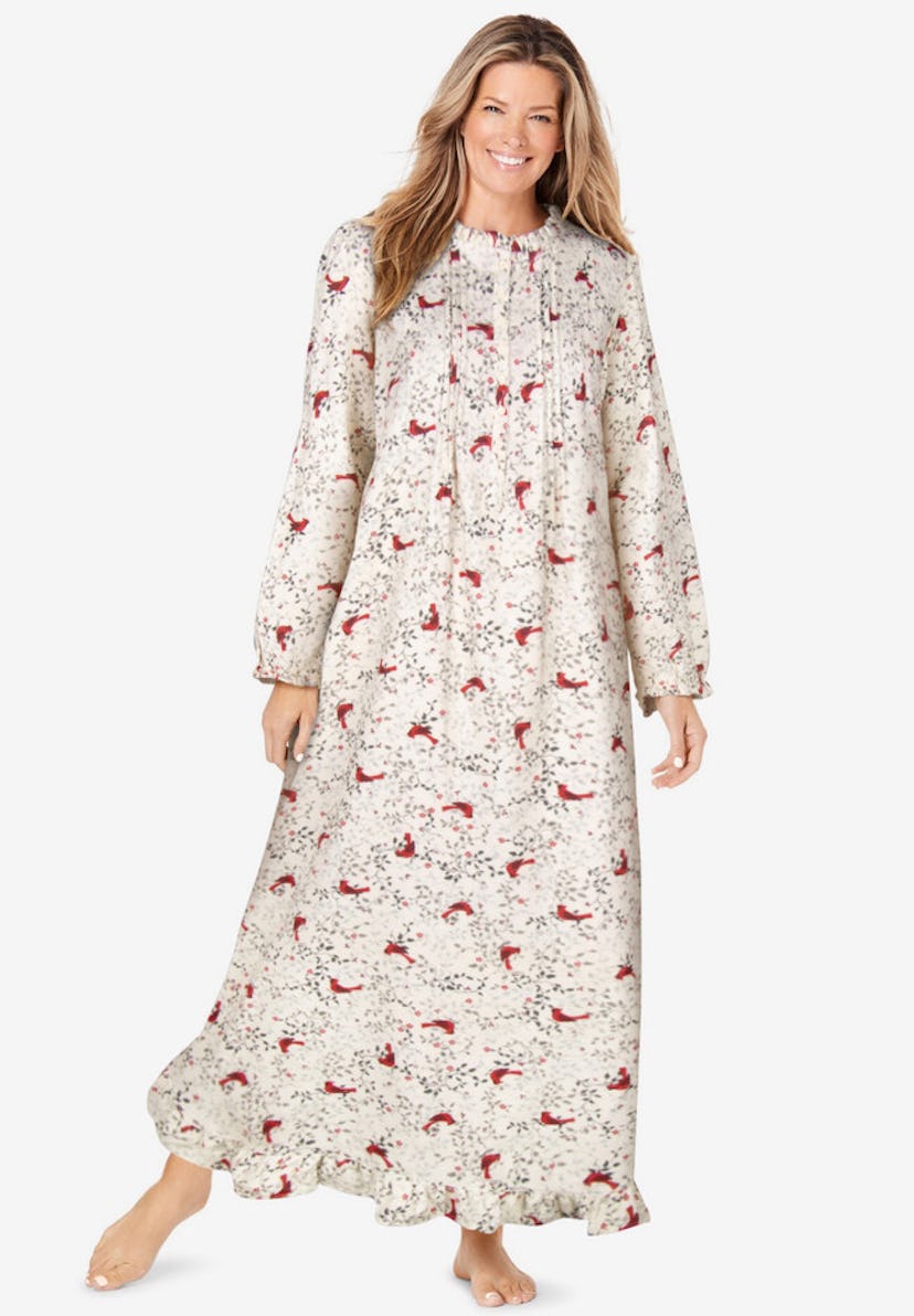 A smiling woman is wearing a long, floral nightgown with a ruffled hem. The gown features a light ba...