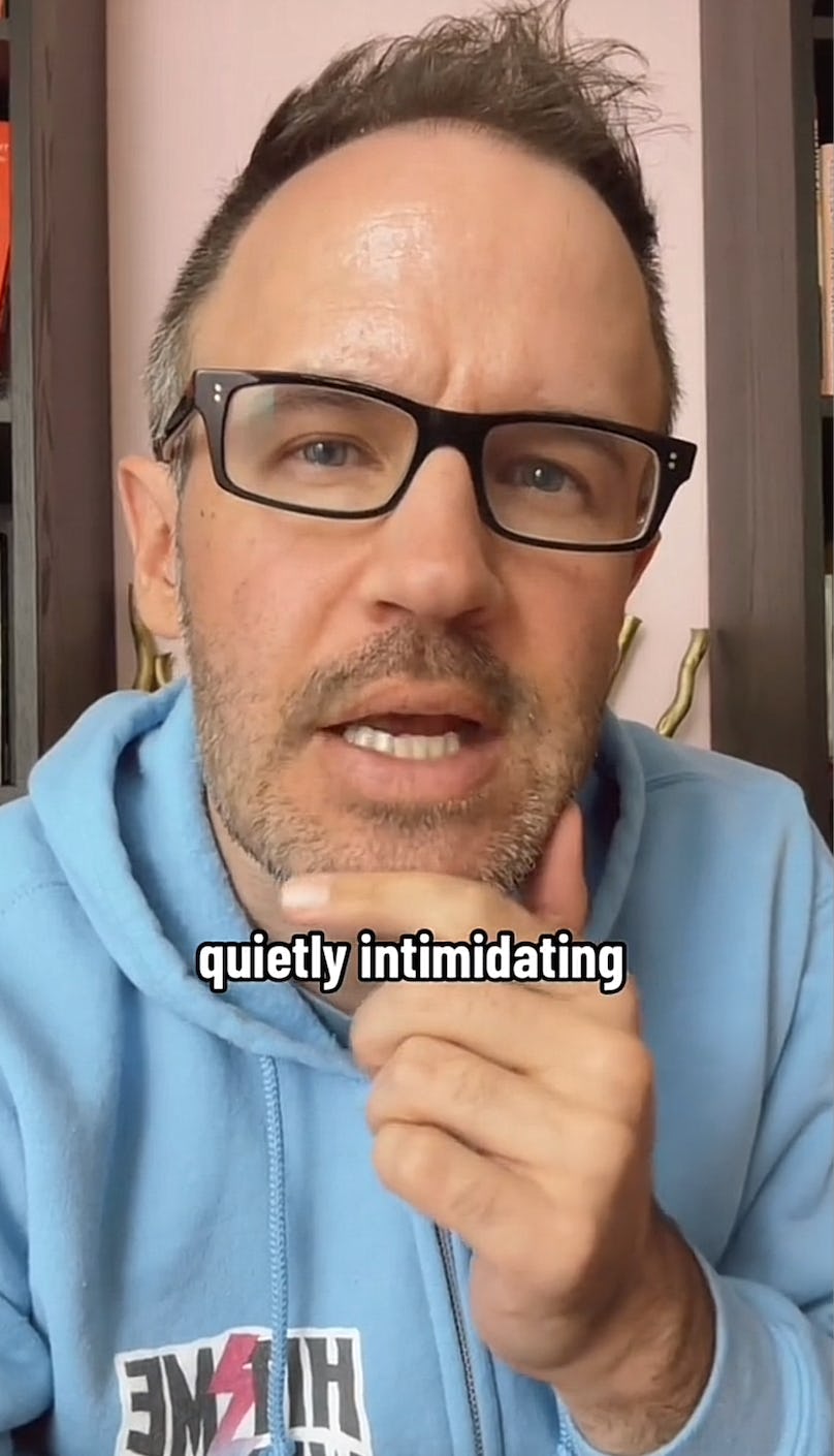 A man in a light blue hoodie, glasses, and a slight beard speaks thoughtfully into the camera, with the text "quietly intimidating" displayed.