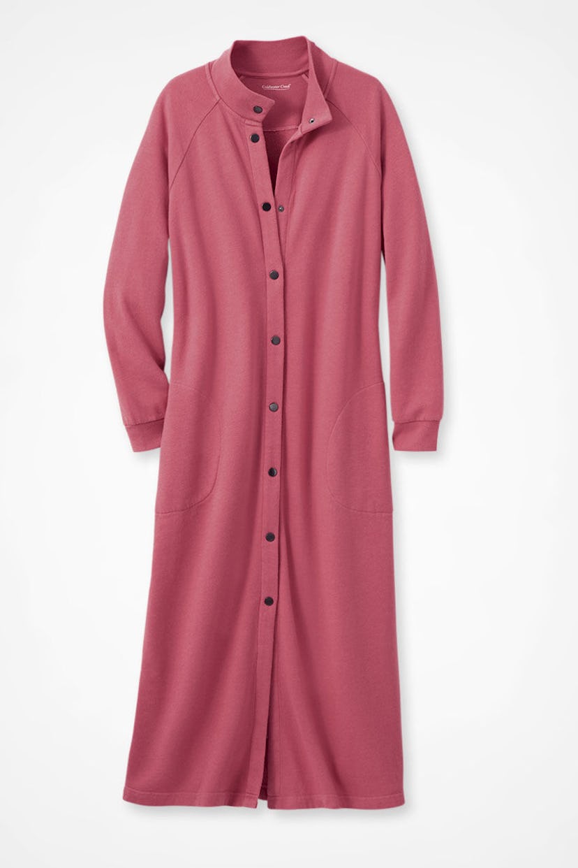 A long, button-up dress in a soft, muted pink color. It features a collar, long sleeves, and two sid...