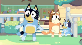 Three cartoon dogs are outside a colorful house. The blue dog with a black patch talks animatedly, w...