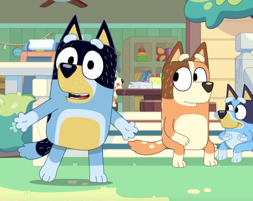 Three cartoon dogs are outside a colorful house. The blue dog with a black patch talks animatedly, w...