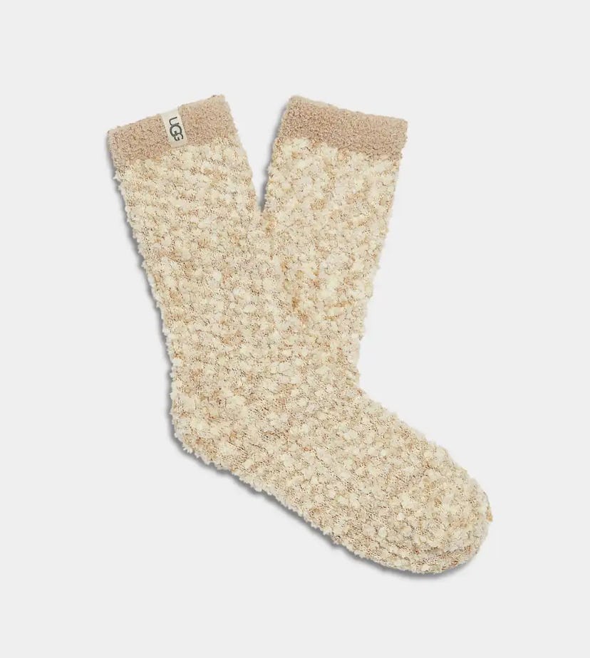 Cozy beige socks with a textured, fluffy design and a soft top band. The socks feature a small logo ...