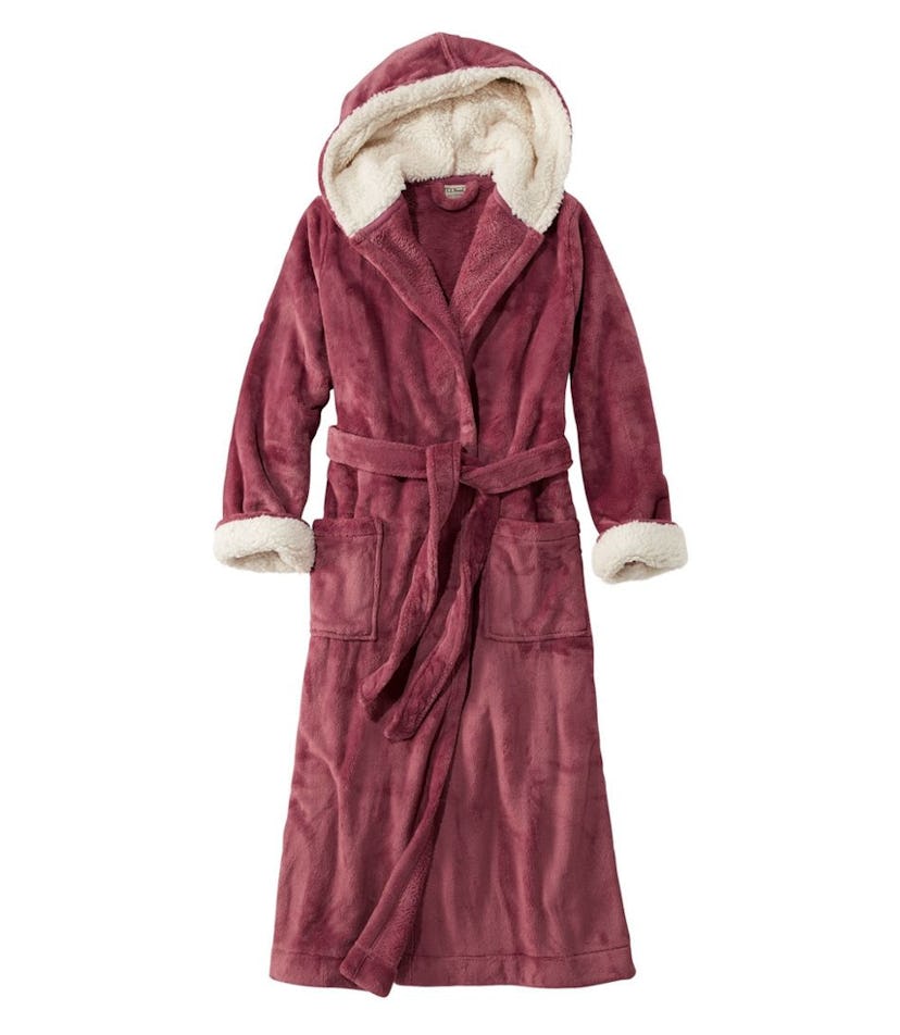 A plush burgundy hooded robe with a soft, cream-colored lining. It features a tie belt, two front po...