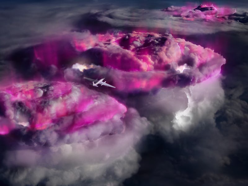 a white airplane flies over black and purple storm clouds