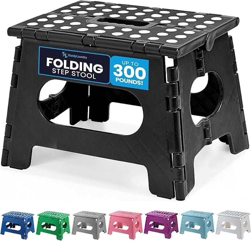 A black, foldable step stool with a textured top, labeled for 300 lbs capacity. It is surrounded by ...