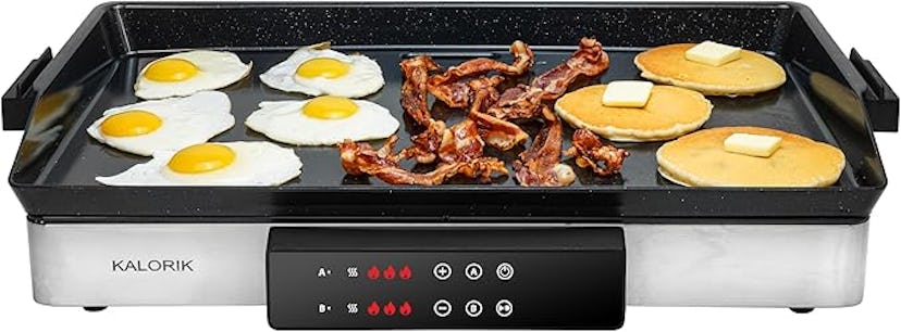 A countertop griddle features sizzling bacon, sunny-side-up eggs, and pancakes with butter, showcasi...