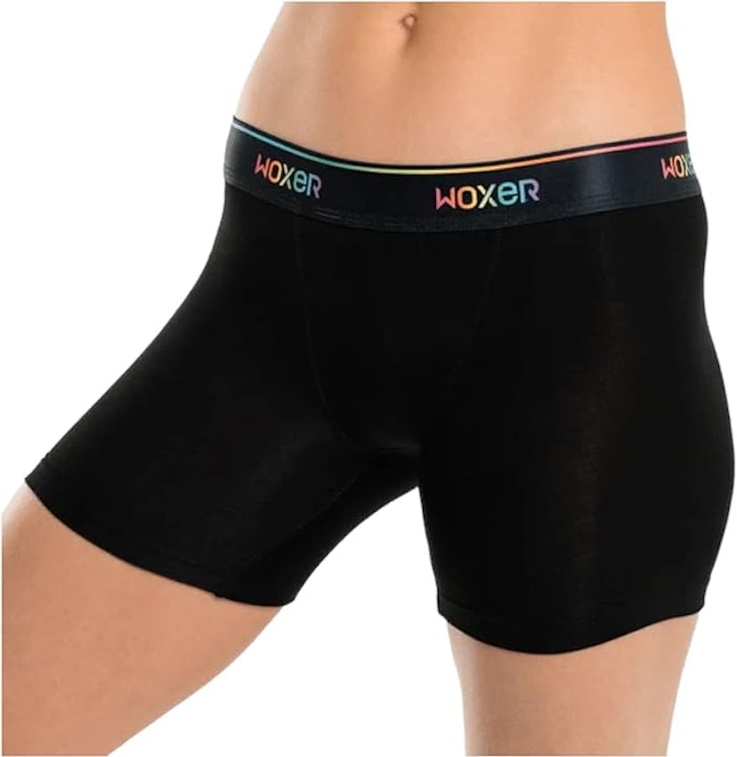 A close-up of a person's lower torso wearing black boxer briefs with a colorful "WOXER" waistband. T...