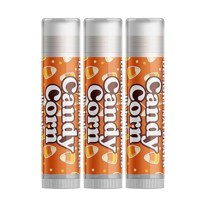 Three tubes of Candy Corn-flavored lip balm are displayed, featuring a festive orange design with ca...