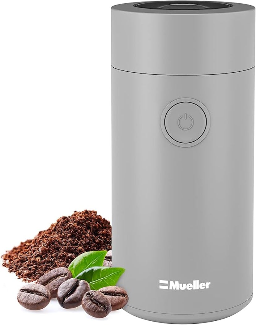 A sleek gray coffee grinder sits next to freshly ground coffee and whole coffee beans, showcasing a ...