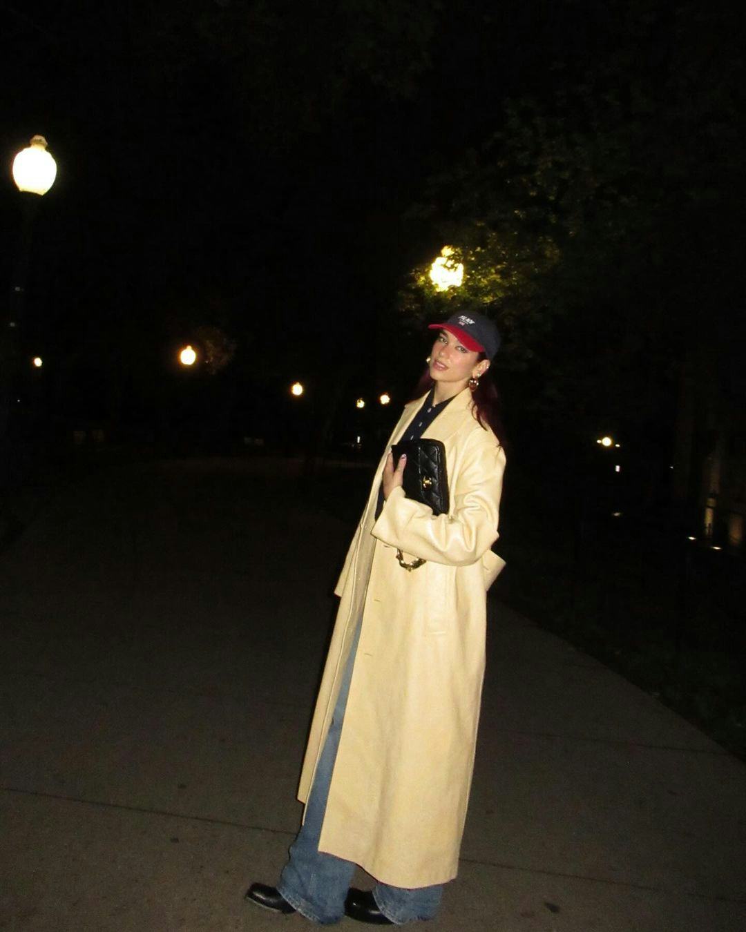 Dua Lipa wears a butter yellow trench coat.