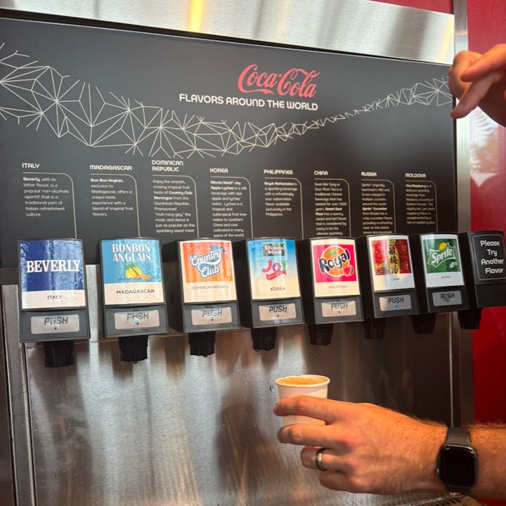 a hand reaches out for the free international coca-cola machine at Epcot
