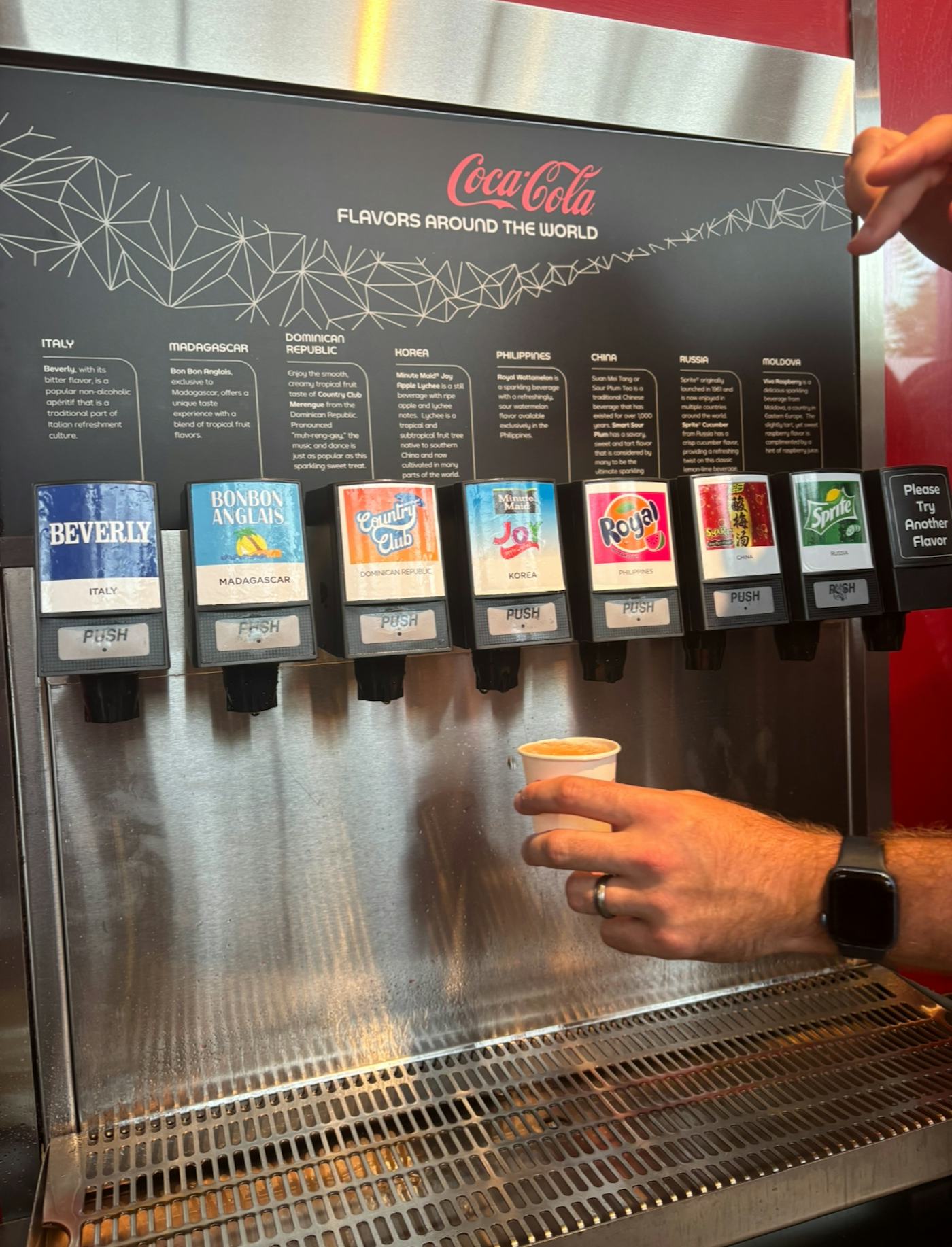 a hand reaches out for the free international coca-cola machine at Epcot